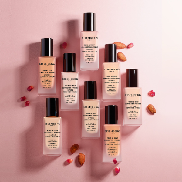 range of skin foundations with almond and pomegranate seeds on a bright pink background