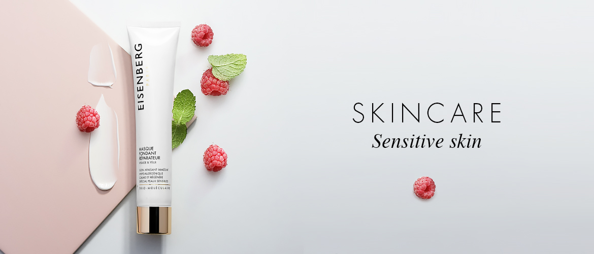 skincare for sensitive skin, the texture of whih is spread next to raspeberries and leaves, all placed against a pink and grey background